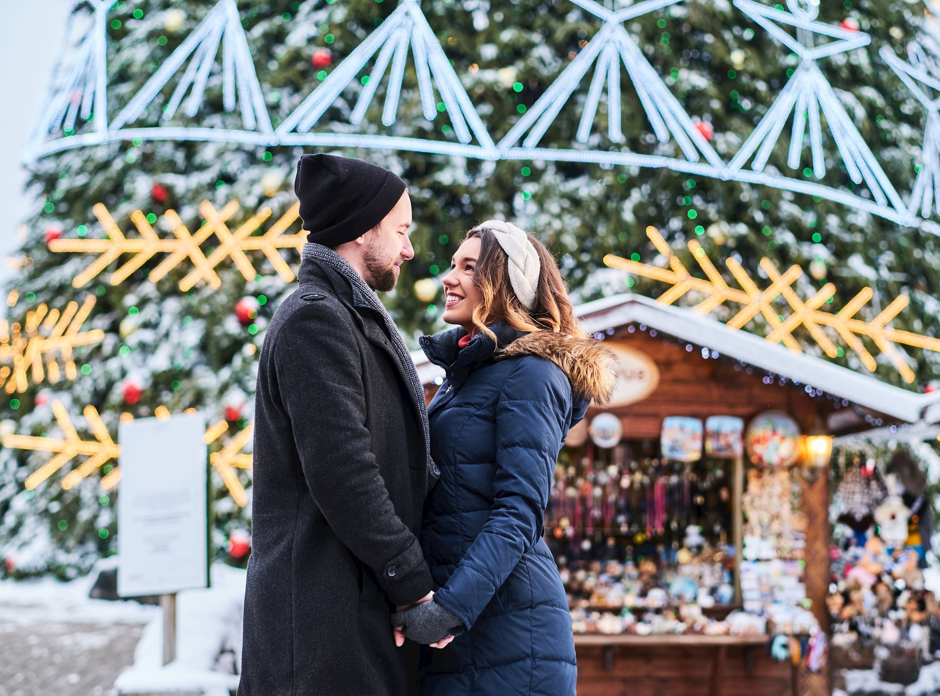 happy-couple-wearing-warm-clothes-hold-hands-look-each-other-standing-near-city-christmas-tree-enjoying-spending-time-together.jpg