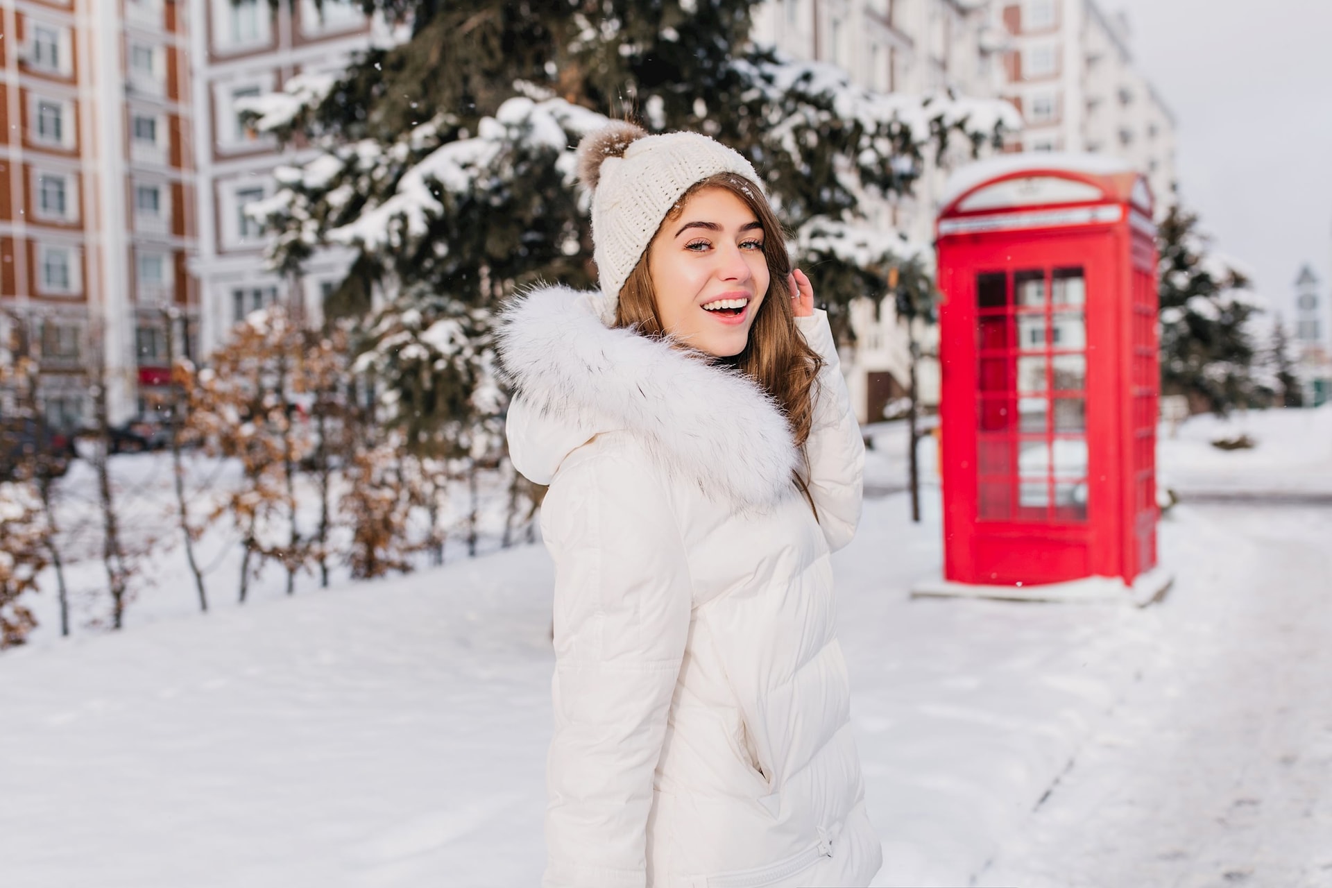 happy-woman-walking-around-winter-sunny-morning-with-smile-fascinating-woman-knitted-hat-looking-shoulder-posing-snowy-street-with-red-telephone-box.jpg