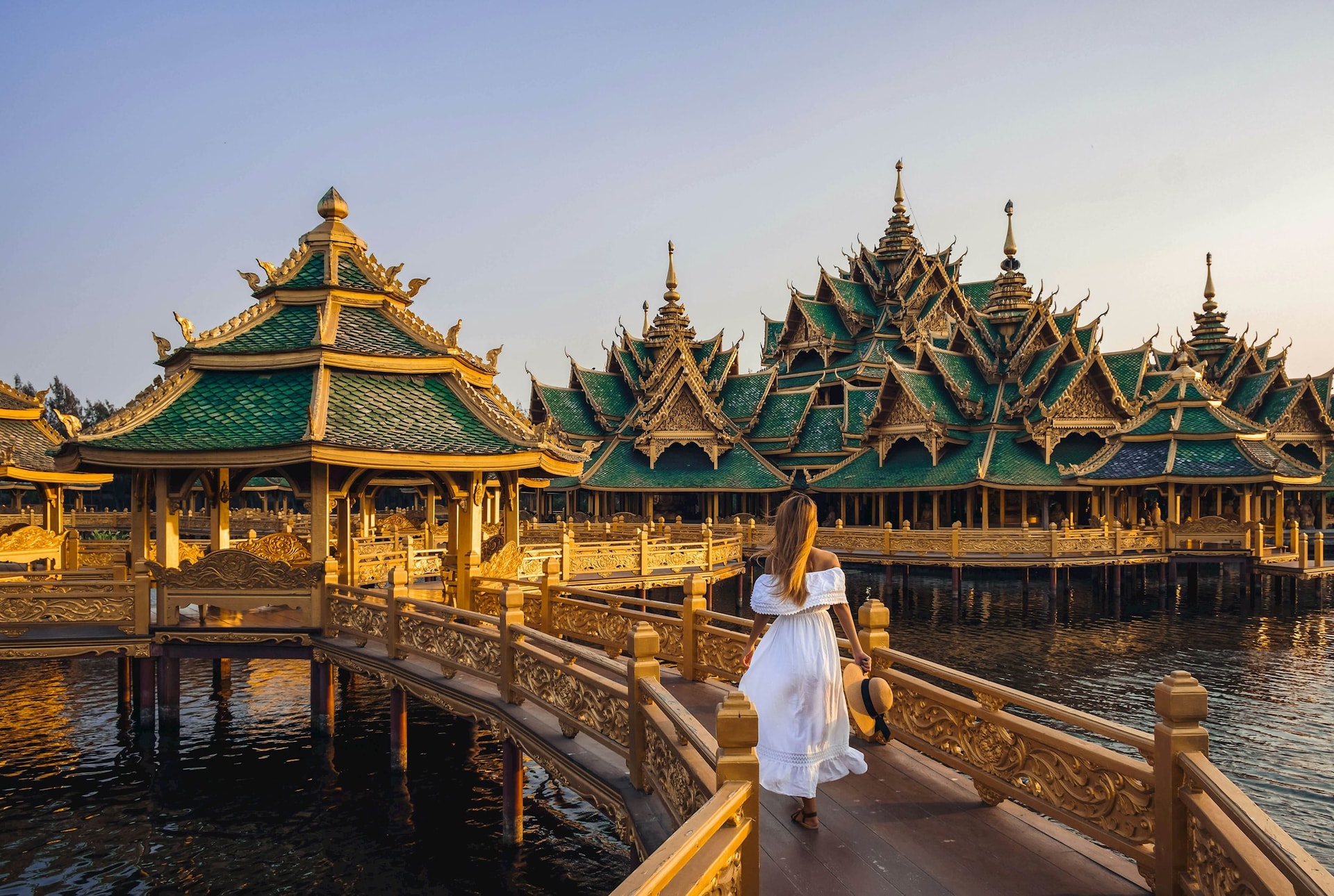 Woman walking on a bridge to Buddhist templae in Thailand during sunset Kiszon Pascal GettyImages-1135361816 rfc