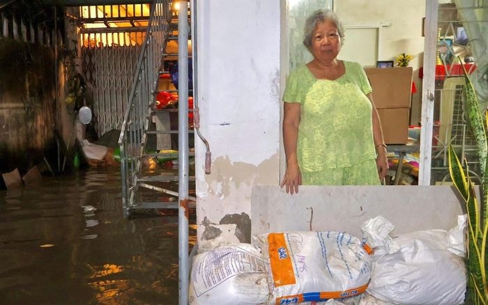  Bà Nguyễn Thị Ngọc Huệ đứng trước những bao cát vừa mua lúc chiều để chắn nước vào nhà. Ảnh: Hồ Lam 